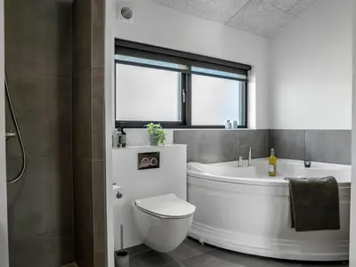 a bathroom with a tub and a toilet and a sink at Holiday Home Eriksine - 750m from the sea by Interhome in Løkken