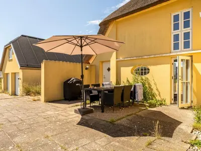 a table with an umbrella in front of a house at Holiday Home Amina - 200m from the sea by Interhome in Blokhus