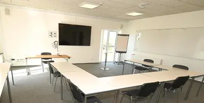 a classroom with tables and chairs and a whiteboard at Sport & Academy in Farsø