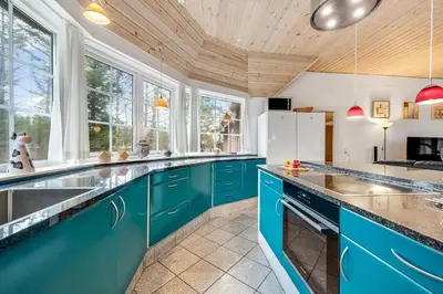 a kitchen with blue cabinets and a wooden ceiling at Family-Friendly Holiday Home With Pool And Spa Close To The North Sea in Harboør