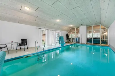a swimming pool with blue water in a building at Family-Friendly Holiday Home With Pool And Spa Close To The North Sea in Harboør