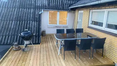a deck with a grill and a table and chairs at Nattely i Thy in Thisted