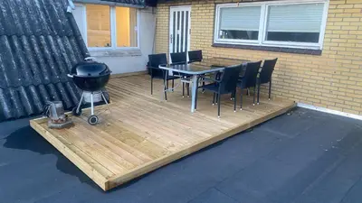 a deck with a grill and a table and chairs at Nattely i Thy in Thisted