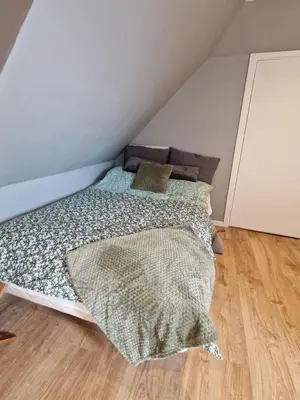 a bedroom with a bed with a comforter and pillows at Stædets lejlighed in Bøvlingbjerg