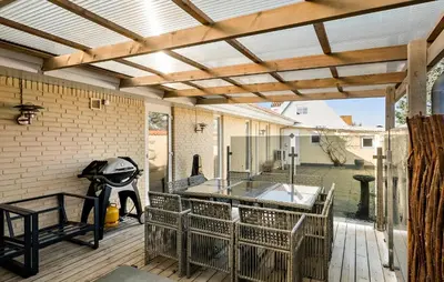 an outdoor patio with a wooden pergola at 5 Bedroom Nice Home In Blokhus in Blokhus