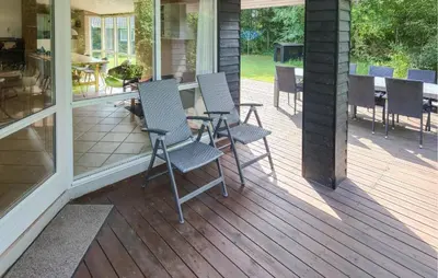 a patio with chairs and tables on a porch at Lovely Home In Fjerritslev With Sauna in Fjerritslev