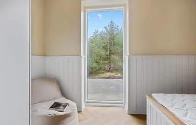a bedroom with a window and a chair and a bed at Beach Front Home In Thyholm With Sauna in Thyholm