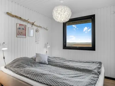 a bedroom with a bed and a window and a chandelier at Holiday Home Waghn - 250m from the sea by Interhome in Harboør