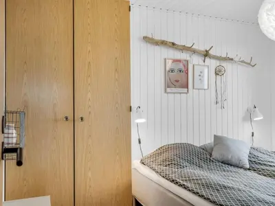 a bedroom with a bed and a wooden cabinet at Holiday Home Waghn - 250m from the sea by Interhome in Harboør