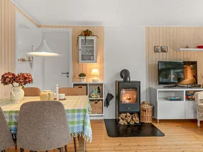 a living room with a table and a fireplace at Holiday Home Annemone - 900m from the sea by Interhome in Blokhus