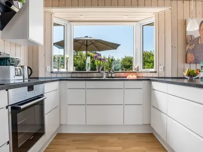a kitchen with white cabinets and a window with an umbrella at Holiday Home Ilya - 1-7km from the sea by Interhome in Saltum