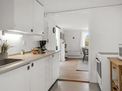 a kitchen with white cabinets and a counter top at Holiday Home Godja - 1km from the sea by Interhome in Blokhus