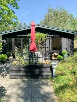 a house with a red umbrella in front of it at Forest Cabin With Panoramic View Near Blokhus in Blokhus