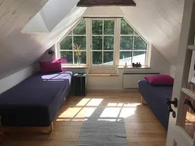 a attic bedroom with two beds and a window at Kornloftet i Lodbjerg in Vestervig