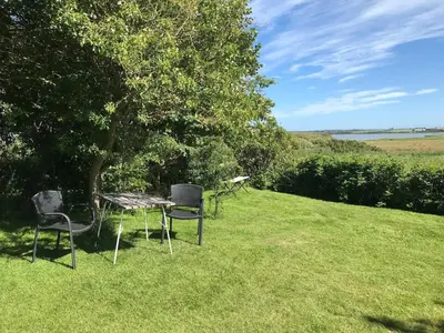 three chairs and a table in a field with a tree at Kornloftet i Lodbjerg in Vestervig