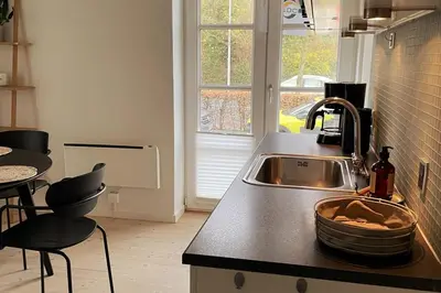 a kitchen with a sink and a table with chairs at Cozy Scandinavian Apartment in the Heart of Viborg in Viborg