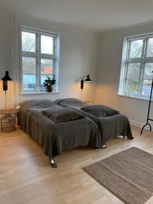 a large bed in a white room with two windows at Modern Scandinavian Apartment in Viborg Centre in Viborg