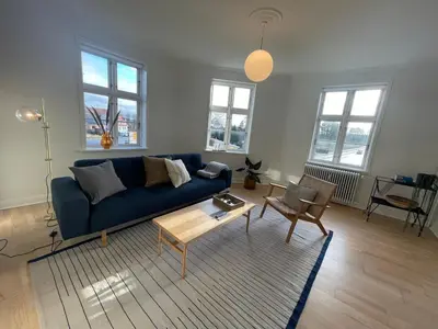 a living room with a blue couch and a table at Modern Scandinavian Apartment in Viborg Centre in Viborg