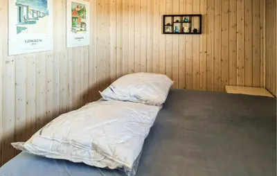 a room with a bed with a white comforter at 3 Bedroom Cozy Home In Løkken in Løkken