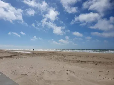 an empty beach with a blue sky and clouds at 4 star holiday home in Løkken in Løgsted