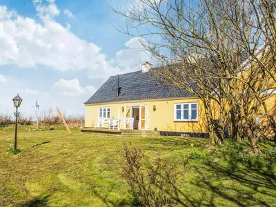 a small yellow house in a field with a yard at 4 star holiday home in Løkken in Løgsted