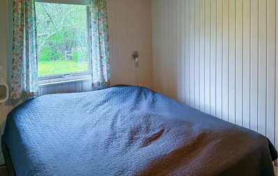 a bedroom with a bed with a blue blanket and a window at 2 Bedroom Nice Home In Roslev in Roslev