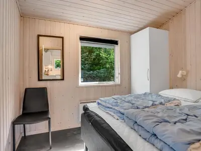 a bedroom with a large bed and a black chair at Holiday Home Onni - 2-3km from the sea by Interhome in Saltum