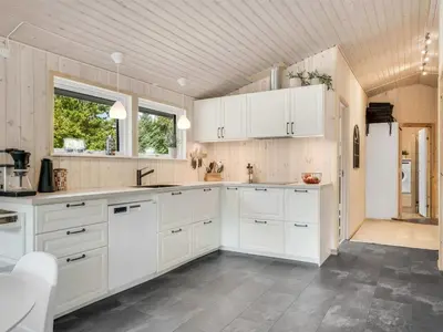 a kitchen with white cabinets and a wooden ceiling at Holiday Home Onni - 2-3km from the sea by Interhome in Saltum