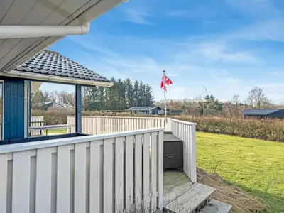 a porch with a white fence and a flag at Holiday Home Anline - 600m to the fjord by Interhome in Farsø