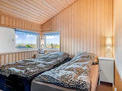 two beds in a room with wooden walls and windows at Holiday Home Anline - 600m to the fjord by Interhome in Farsø