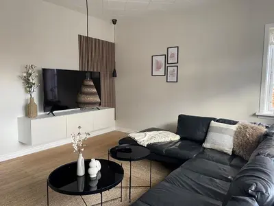a living room with a black couch and a tv at Stor lys lejlighed på 100 kvm, central beliggenhed in Holstebro