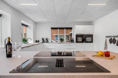 a kitchen with white cabinets and a counter with a sink at Exclusive Pool Houseconference Center With Gymnasium in Erslev