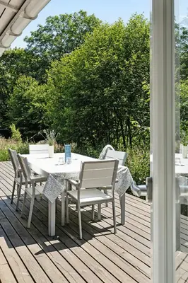 a table and chairs on a wooden deck at Forest House With Stream By Hjarbæk Fjord in Højslev