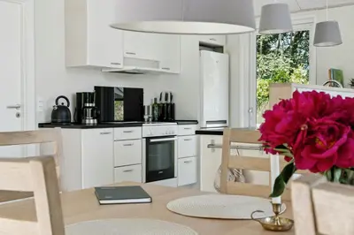 a kitchen with a table and a vase with a flower at Forest House With Stream By Hjarbæk Fjord in Højslev