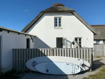 a surfboard laying on the ground in front of a house at North Sea Atmosphere On The Farm In Klitmøller in Torsted