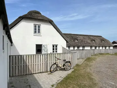 a bike parked in front of a white house with a thatch roof at North Sea Atmosphere On The Farm In Klitmøller in Torsted