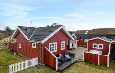 a red house with a wooden deck at Nice Home In Blokhus With Wifi in Blokhus