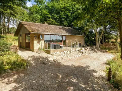 a small house with glass windows in a field at Cozy Holiday Home Near Lild Strand in Frøstrup