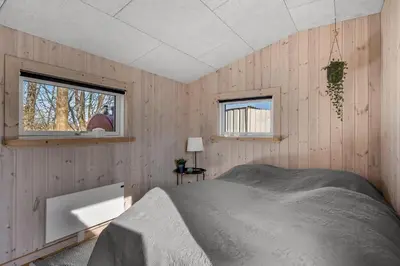a bedroom with wooden walls and a bed in a room at Holiday Home With Pool And Spa Close To The Limfjord in Roslev