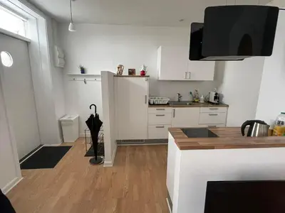 a kitchen with white cabinets and a wooden floor at Cozy base near the cathedral in Viborg
