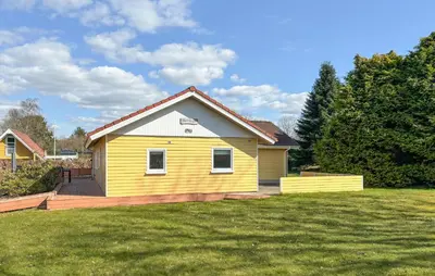 a yellow house with a deck in a yard at Stunning Home In Farsø With Wifi in Farsø
