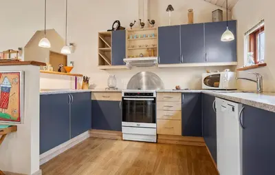 a kitchen with blue cabinets and a white stove top oven at Cozy Home In Spøttrup With Sauna in Spottrup