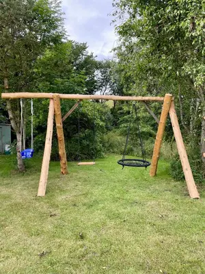a wooden swing set in a yard with grass at Surfreservatet i Nationalpark Thy in Hanstholm