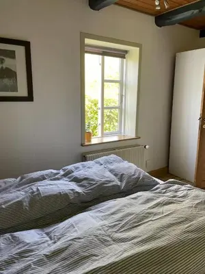 an unmade bed in a bedroom with a window at Surfreservatet i Nationalpark Thy in Hanstholm