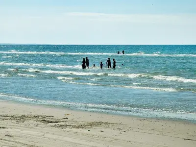 a group of people standing in the water at the beach at 4 star holiday home in Brovst in Brovst