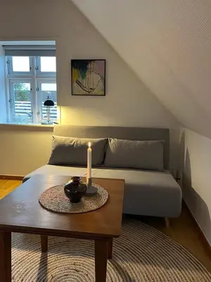 a living room with a bed and a table with a candle at Bright Nordic Loft Apartment in Spottrup