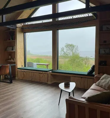 a living room with a large window with a pool table at Modern Wooden House Near Halkær Bredning in Nibe