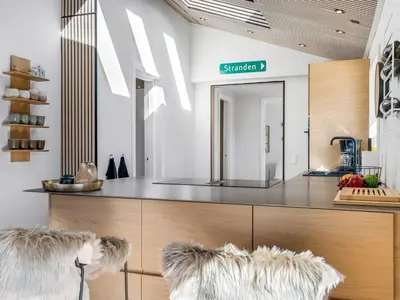 a kitchen with a counter with two furry chairs at Holiday Home Heidl - 2km from the sea by Interhome in Blokhus