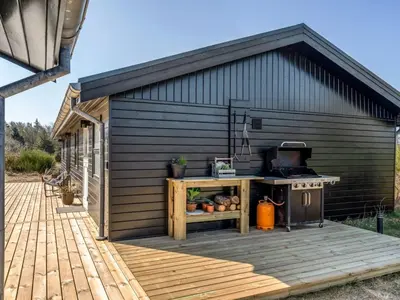 a barbecue on a deck next to a building at Holiday Home Heidl - 2km from the sea by Interhome in Blokhus