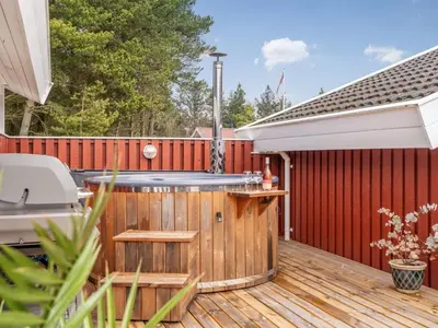 a hot tub on a deck with a fence at Holiday Home Gunborg - 2-5km from the sea by Interhome in Blokhus